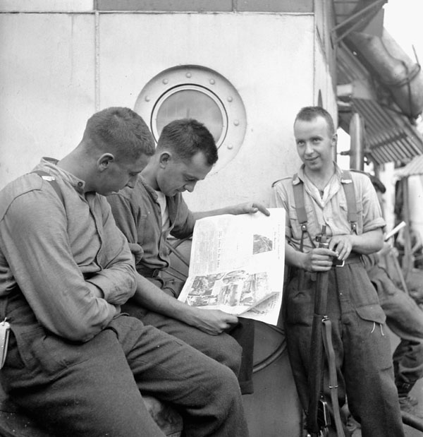 Infantrymen of the 9th Canadian Infantry Brigade aboard an LCI, reading the news of the Canadian entry into Rome.