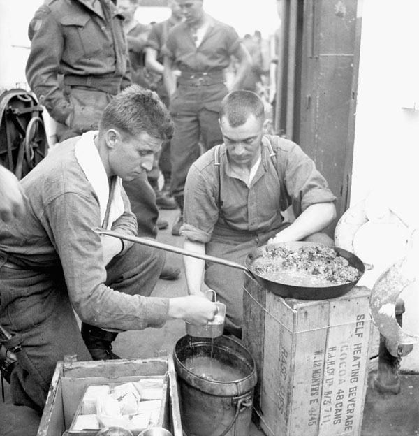Infantrymen of The Highland Light Infantry of Canada cooking a meal aboard LCI 306.