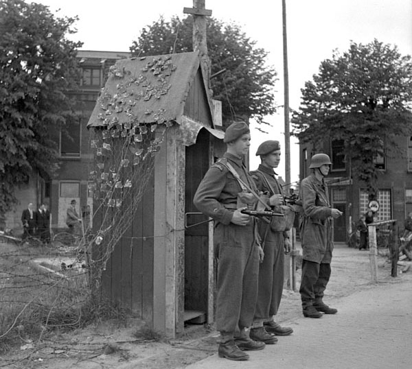 Canadian Corps soldiers on guard duty with a German soldier, also on guard duty, at the German prisoner of war garrison